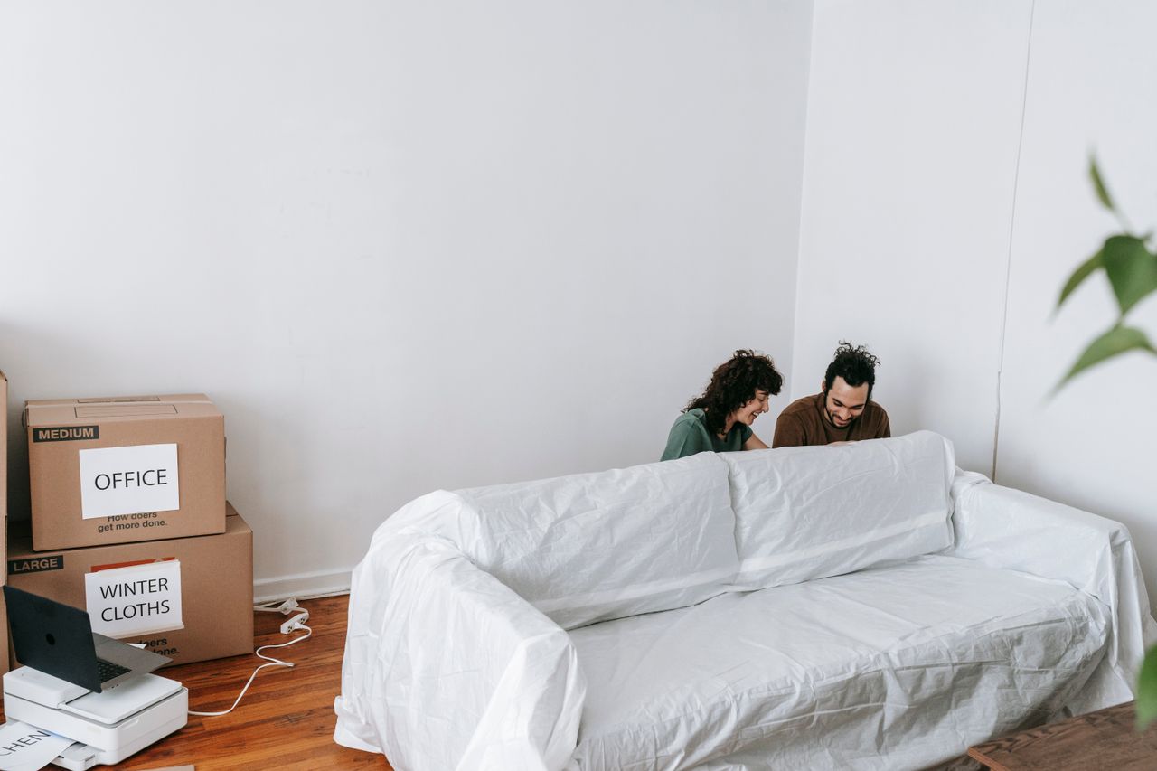 A couple enjoys moving into a new home, surrounded by boxes and minimalist decor.